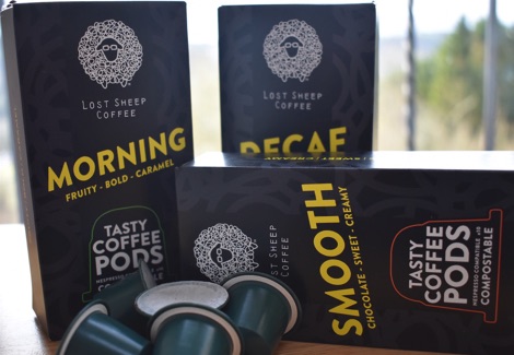 Three boxes of Lost Sheep Coffee pods, with green coffee pods, on a table